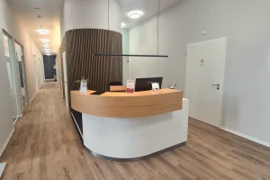 Empfang am Standort Bielefeld mit geschwungenem Holztresen und hellem Flur